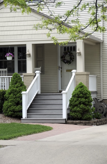 An image of the front of a house, with a brick pathway and steps up to a porch