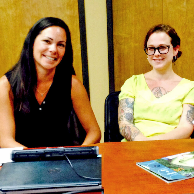 An image of two women sitting at a table smiling